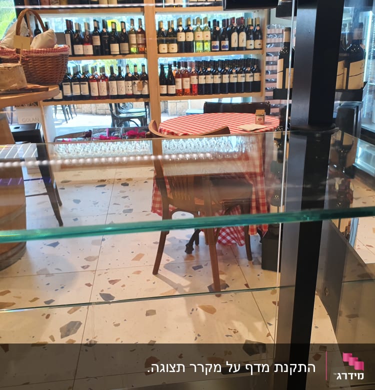 מדף זכוכית שקוף בחנות עם בקבוקי יין ברקע